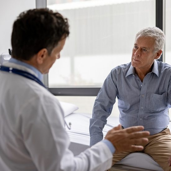 Latin American doctor talking to a patient in a consultaton at his office practice - healthcare and medicine concepts